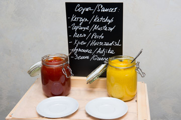 Sauces in glass jars on a table in a restaurant.