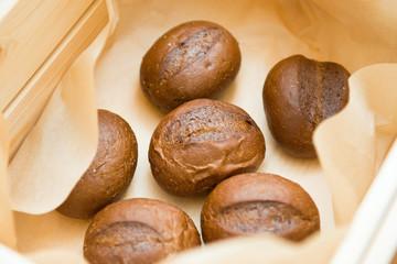 Close-up of rye buns in a basket on a table.