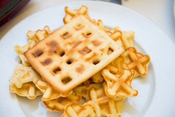 Fresh waffles in a white plate on the table close-up.