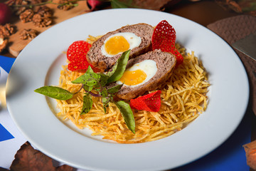 Chopped steak with egg and french fries in a plate on a decorated table close-up. Restaurant dishes.