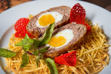 Chopped steak with egg and french fries in a plate on a decorated table close-up. Restaurant dishes.