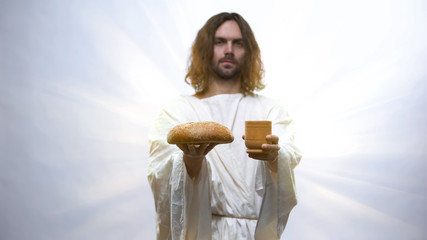 Jesus holding wine and bread on illuminated background, Christian ceremony