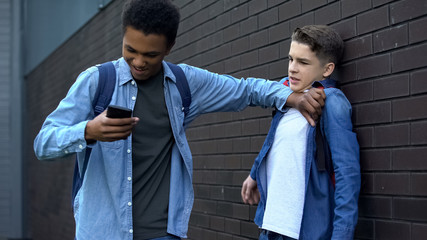 Black teenager taking away phone from boy, making fun of social media account