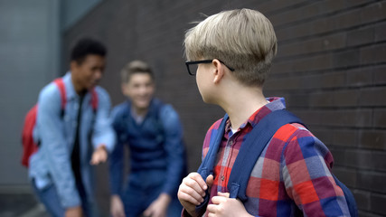 Cruel teenagers laughing at new boy in school, calling names, verbal bullying
