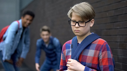 Evil teen boys laughing at new student in school, calling names, verbal bullying