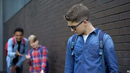 Teenagers mocking boy in eyeglasses, spreading malicious rumors, verbal bullying