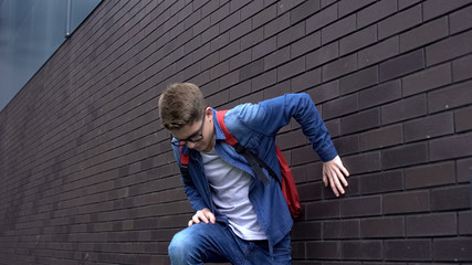 Schoolboy lying near wall, feeling unwell, suffering sudden pain, health problem