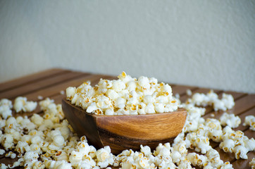 Salted popcorn on a wooden table. White popcorn flakes in a wooden bowl. Selective focus image.