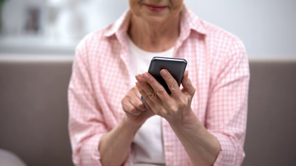 Smiling aged woman using smartphone, application for elderly people, technology