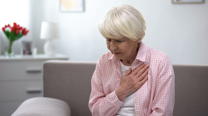 Old woman with heart disease holding hand on chest, suffering from tachycardia