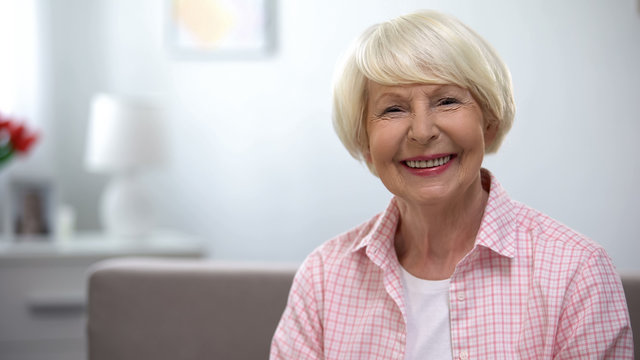 Happy elderly woman smiling at camera, social security, retirement benefits