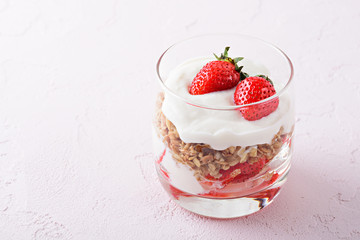 dessert with whipped cream, granola and strawberries on pink background