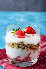 vertical image of dessert with strawberry, granola and curd mousse on blue grey background