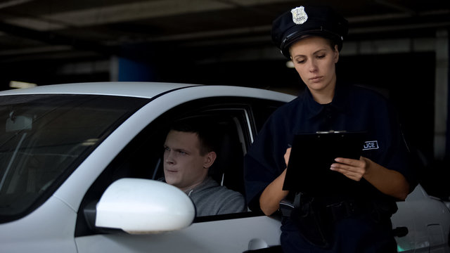 Female Officer Writing Traffic Ticket To Male Driver For Parking Violation, Fine