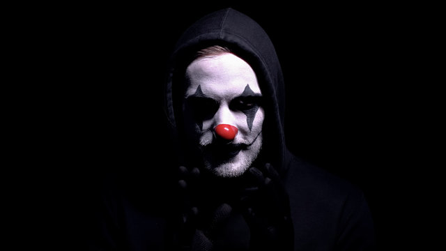 Crazy man in spooky clown mask staring at camera, murder or robbery threat