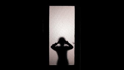 Little girl silhouette watching through glass door, spooky paranormal phenomena
