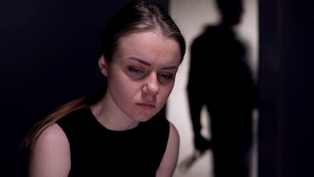 Depressed woman feeling frustrated, husband with vodka bottle behind, addiction