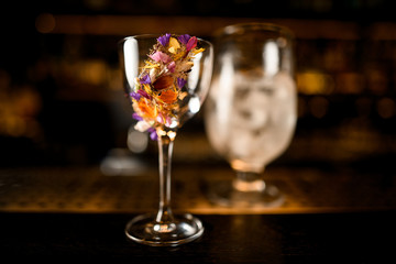 Glass decorated with a different multicolored flowers standing in tha bar