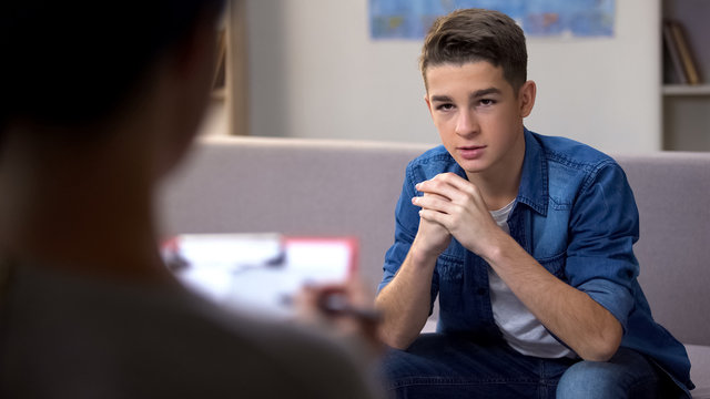 Anxious teenager visiting psychologist for personal therapy session, problems