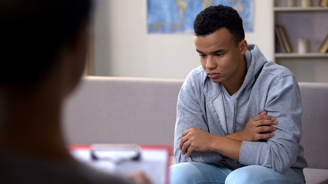 Depressed African-American Teenager Talking To Psychologist, Racism At School