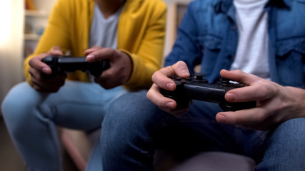 Multiracial friends playing computer games, closeup on hands with joysticks