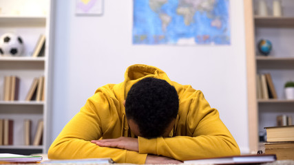 Overworked african-american student napping preparing for test, lack of energy