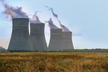 Cooling towers of the atomic power station against the sunset with vapor steam coming out.