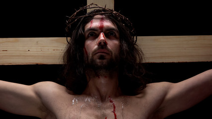Crucified savior in thorns crown looking up, sins forgiveness religious history