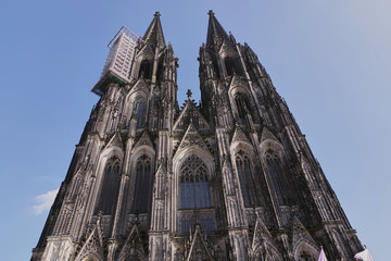 View over amazing, gothic, richly decorated facade of the Cologne Cathedral (Kolner Dom) against clear blue sky. World heritage and famous landmark of the city of Cologne, Germany.