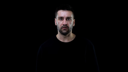 Obraz premium Scared male looking camera on black background, nightmare horror, shock stress