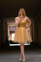 girl in a prom dress with sequins poses against the background of poor old houses of the city