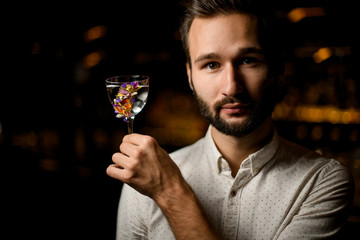 Professional bartender presenting a cocktail in the glass decorated with flowers