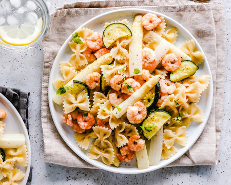 Shrimp, courgette and asparagus pasta with a glass of water