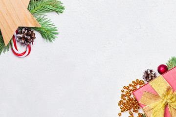 Christmas gift, green Xmas fir branch, red holly berries and baubles on white stucco plaster...
