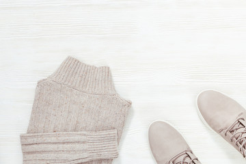 Plakat Light leather shoes and knitted Womens pullover on white wooden surface with copy space. Female clothes. Shopping and sale concept. View from above.