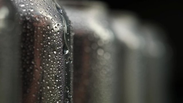 transparent large Drop of water slowly flows down the surface of the aluminum cans. Panoramic macro photography with Studio lighting.