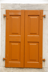 Closed brown rustic wooden window on stone wall.
