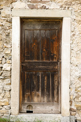 Old vintage brown wooden doors in stone wall.