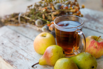 autumn harvest composition with apples pears cup of tea and dry healing herbs on wooden blue table background