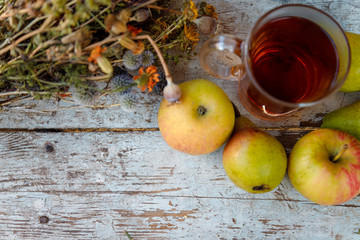 autumn harvest composition with apples pears cup of tea and dry healing herbs on wooden blue table background
