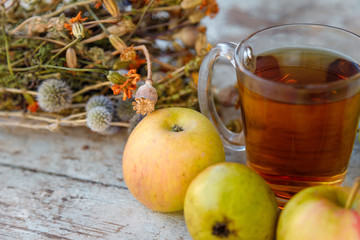 autumn harvest composition with apples pears cup of tea and dry healing herbs on wooden blue table background