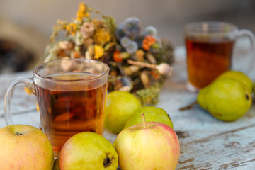 autumn harvest composition with apples pears cup of tea and dry healing herbs on wooden blue table background