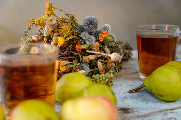 autumn harvest composition with apples pears cup of tea and dry healing herbs on wooden blue table...
