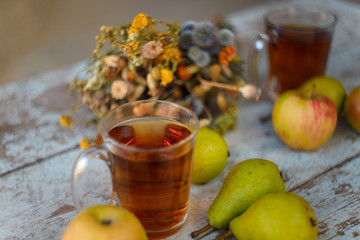 autumn harvest composition with apples pears cup of tea and dry healing herbs