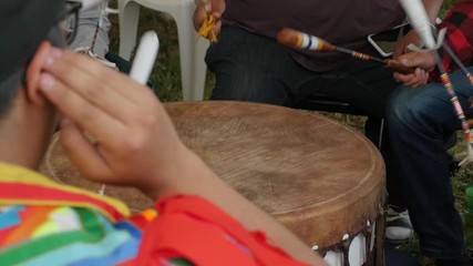 Native American men in a drum group hit drum at pow wow