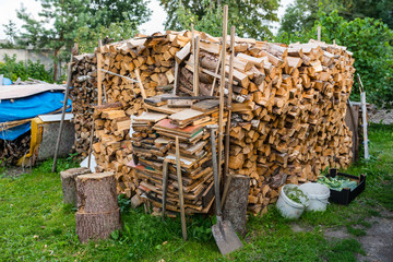 A firewood stacked in a pile, cut trunks. lying behind the house.