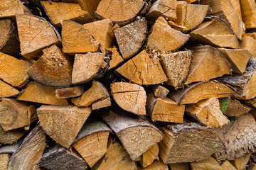 A firewood stacked in a pile, cut trunks. Close up shot, wood background.
