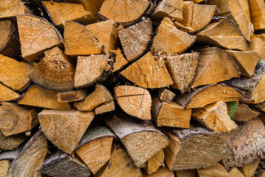 A firewood stacked in a pile, cut trunks. Close up shot, wood background.