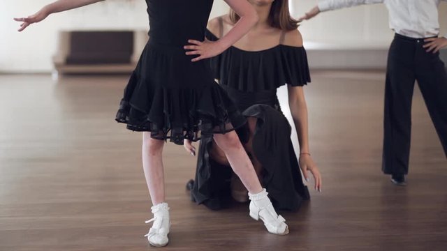 Handheld shot of a beautiful young dance teacher giving a cute boy and girl children dancing lesson in class