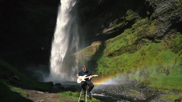 Man playing guitar in front of a beautiful waterfall in Iceland. SlowMo and real time shots from the Sony a7iii and Ronin S.
